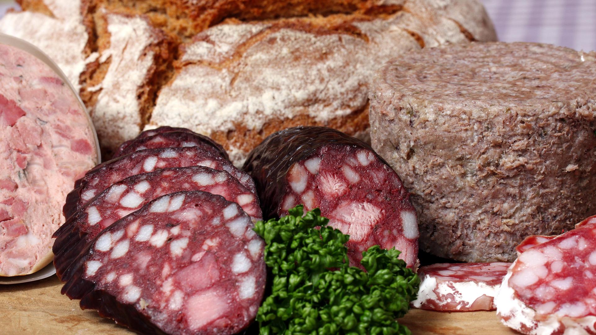 Auf dem Bild ist eine Brotzeit mit verschiedenen Wurstsorten und einem Laib Brot zu sehen.