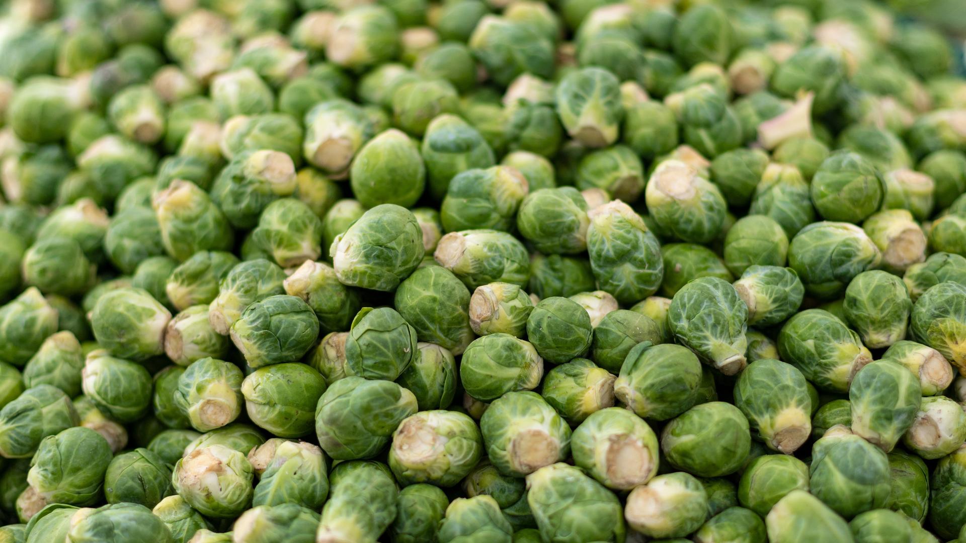 An einem Verkaufsstand für Gemüse auf einem Markt liegt zahlreicher Rosenkohl, Rosenkohlknospen. An einem Verkaufsstand für Gemüse auf einem Markt liegt zahlreicher Rosenkohl, Rosenkohlknospen.