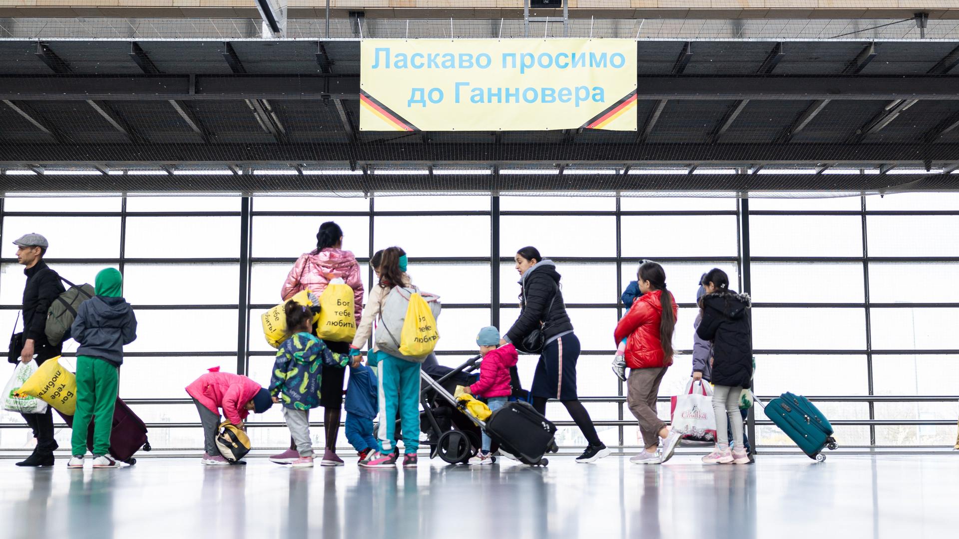 Ukrainische Geflüchtete laufen von rechts nach links durch eine Bahnhofshalle. Ukrainische Geflüchtete laufen von rechts nach links durch eine Bahnhofshalle.