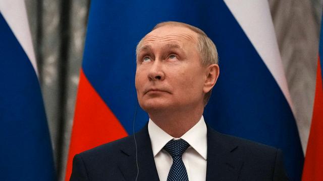 Wladimir Putin mit nach oben gerichteten Blick. Im Hintergrund ist die russiche Flagge zu sehen.