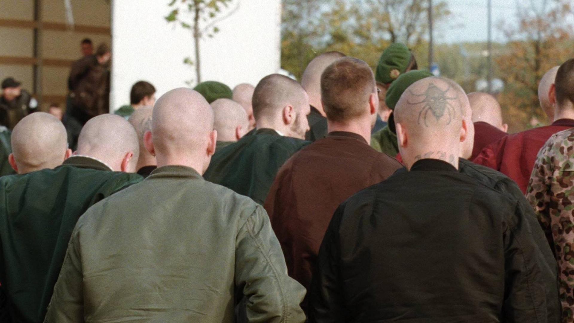 Männer mit Glatzen und in Bomberjacken sind von hinten auf einer Demonstration zu sehen. Männer mit Glatzen und in Bomberjacken sind von hinten auf einer Demonstration zu sehen.