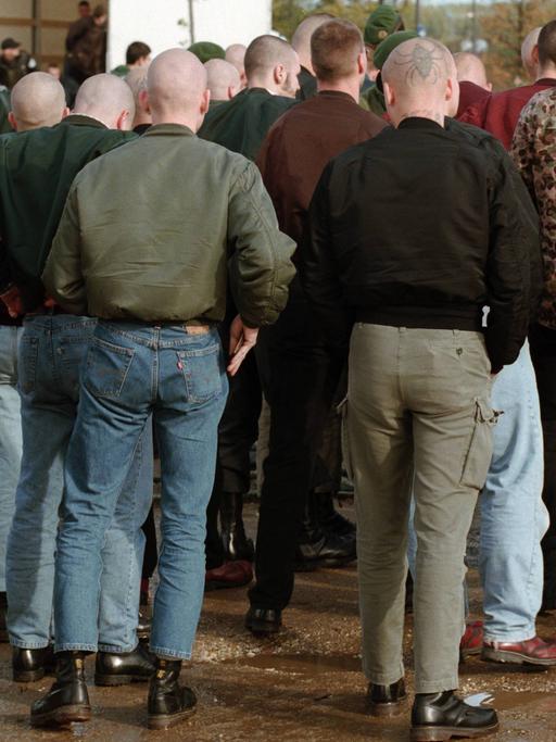 Männer mit Glatzen und in Bomberjacken sind von hinten auf einer Demonstration zu sehen.