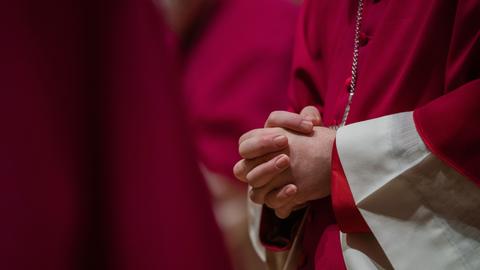 Blick auf die zum Gebet gefalteten Hände eines Bischofs
