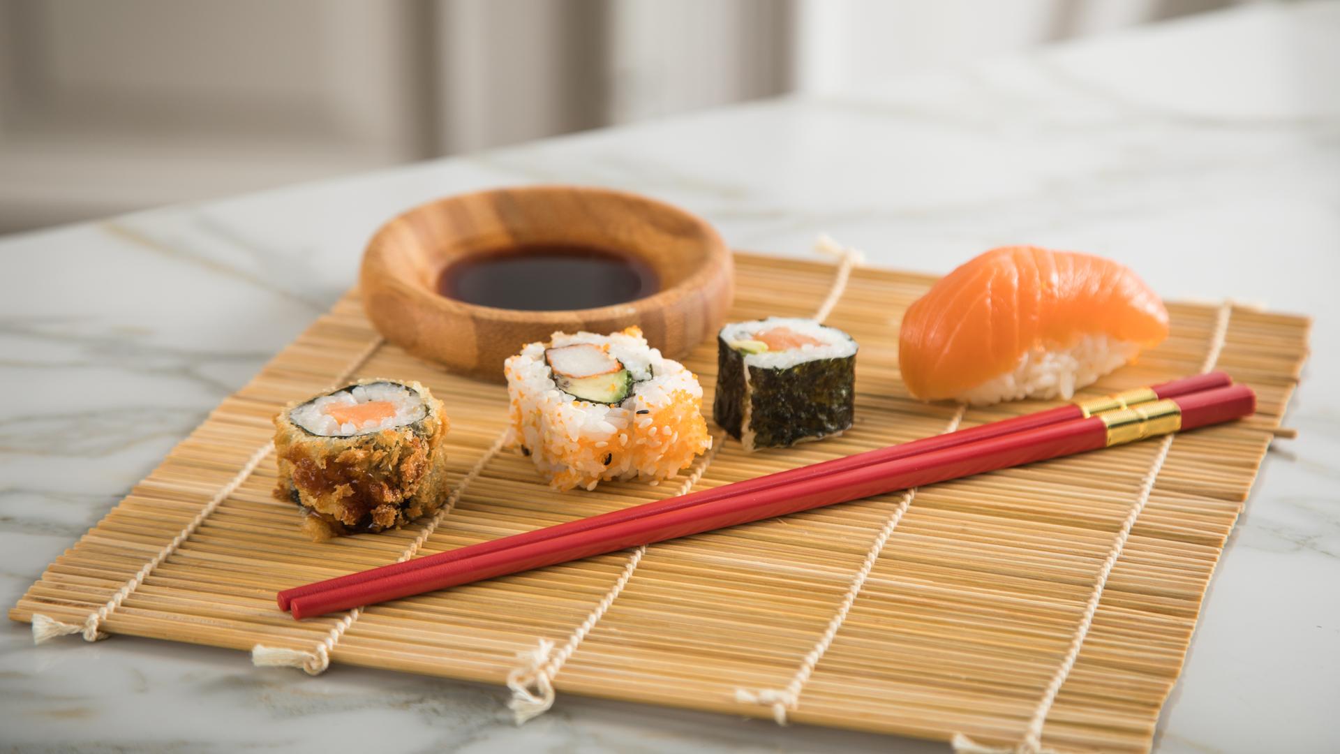 Verschiedene Sushi-Varianten auf einer Sushimatte angerichtet. Verschiedene Sushi-Varianten auf einer Sushimatte angerichtet.