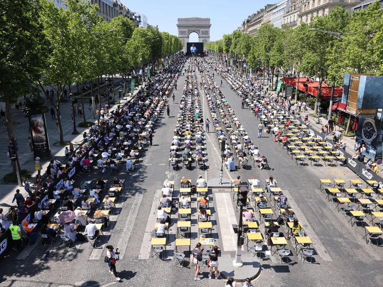 Schreibpulte für bis zu 1.700 Teilnehmende auf der Prachtstraße bis hin zum Triumphbogen in Paris.