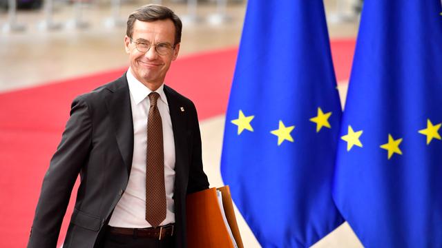Der schwedische Ministerpräsident Ulf Kristersson läuft vor EU-Fahnen entlang und lächelt in die Kameras