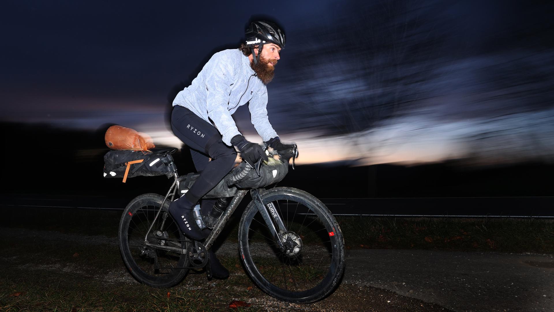Extrem-Sportler Jonas Deichmann fährt nach seiner Grenzüberfahrt aus der Schweiz mit seinem Fahrrad auf einem Feldweg. Nach seinem Triathlon um die Welt kam Deichmann in Baden-Württemberg an.