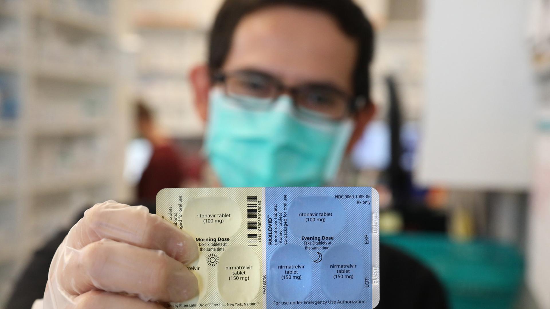 Jemand hält ein Päckchen des Medikaments Paxlovid des US-Herstellers Pfizer in die Kamera Jemand hält ein Päckchen des Medikaments Paxlovid des US-Herstellers Pfizer in die Kamera