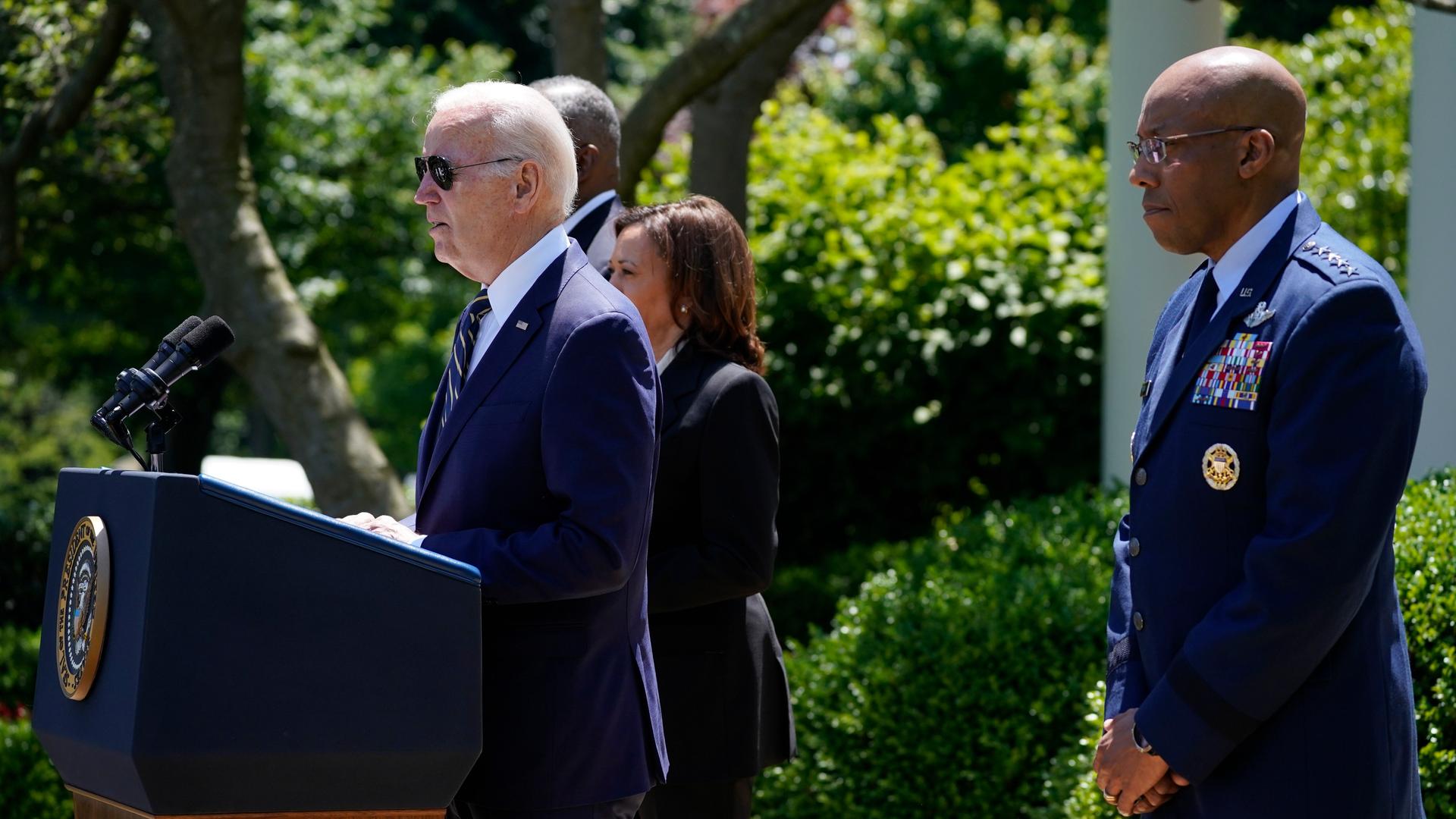Joe Biden steht an einem Redepult im Freien, rechts versetzt hinter ihm steht Charles Brown. Im Hintergrund ist grüne Flora zu erkennen. Joe Biden steht an einem Redepult im Freien, rechts versetzt hinter ihm steht Charles Brown. Im Hintergrund ist grüne Flora zu erkennen.