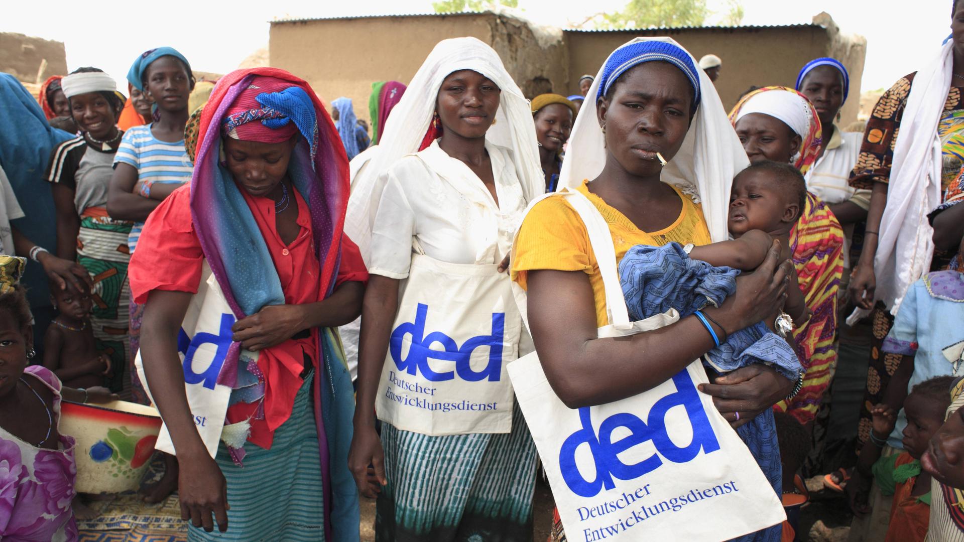 Frauen in einem Dorf der Region FadaNgourma in Burkina Faso tragen Taschen mit dem Logo des DED (Deutscher Entwicklungsdienst). Frauen in einem Dorf der Region FadaNgourma in Burkina Faso tragen Taschen mit dem Logo des DED (Deutscher Entwicklungsdienst).