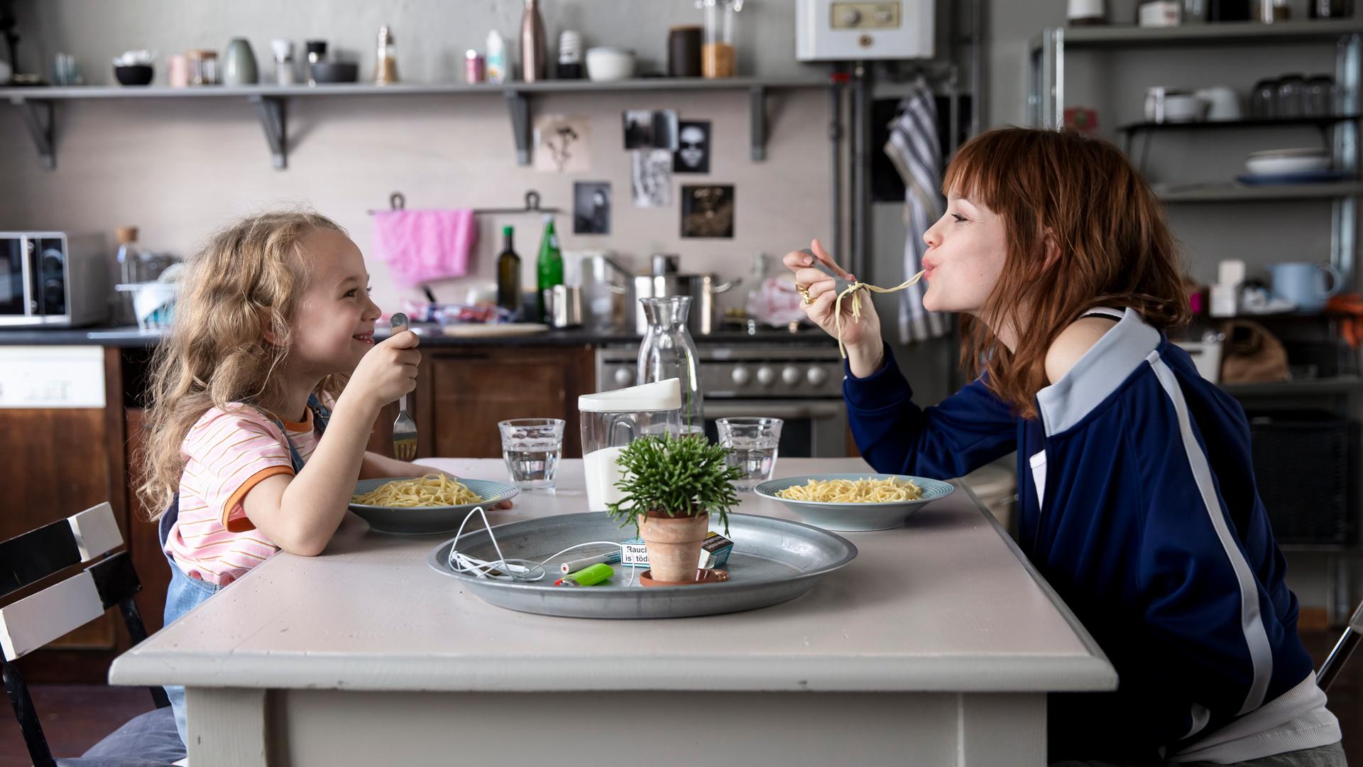 Szene aus dem Film "Wunderschön". Rechts im Bild Karoline Herfurth als Mutter Sonja, links ihre Filmtochter. Beide essen Spaghetti. Szene aus dem Film "Wunderschön". Rechts im Bild Karoline Herfurth als Mutter Sonja, links ihre Filmtochter. Beide essen Spaghetti.