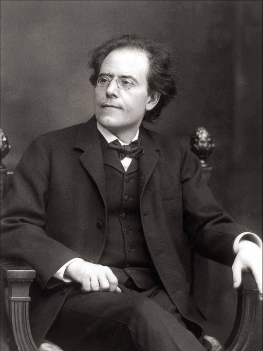 Gustav Mahler sitzt auf einem Stuhl. Das Foto ist in schwarz-weiß.