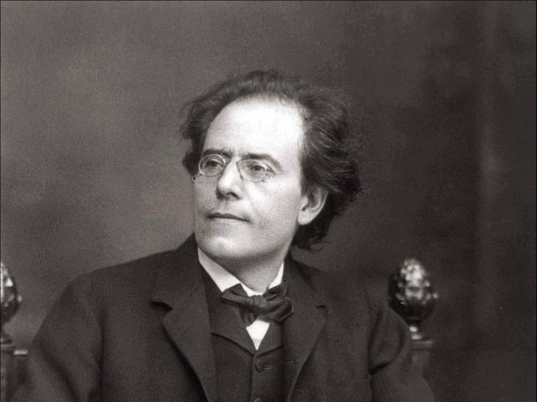 Gustav Mahler sitzt auf einem Stuhl. Das Foto ist in schwarz-weiß.