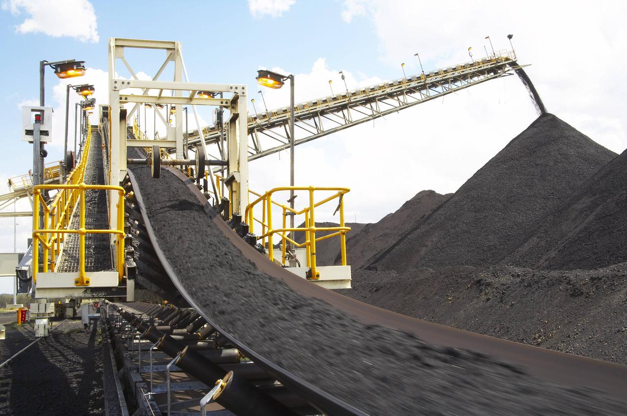 Ein Förderband transportiert Kohle in die Höhe, die auf einem großen schwarzen Berg abgeladen wird. Ein Förderband transportiert Kohle in die Höhe, die auf einem großen schwarzen Berg abgeladen wird.