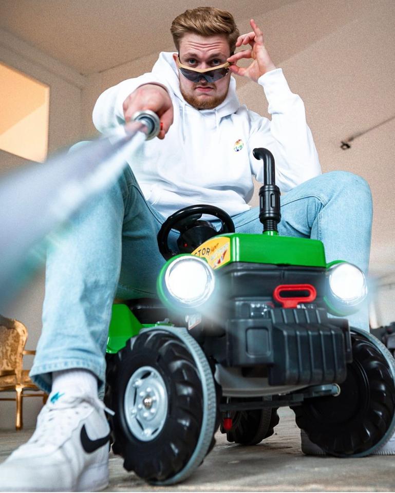 Ein Mann auf einem Spielzeugauto hält ein Spielzeug-Laserschwert oder Ähnliches in die Kamera. Ein Mann auf einem Spielzeugauto hält ein Spielzeug-Laserschwert oder Ähnliches in die Kamera.
