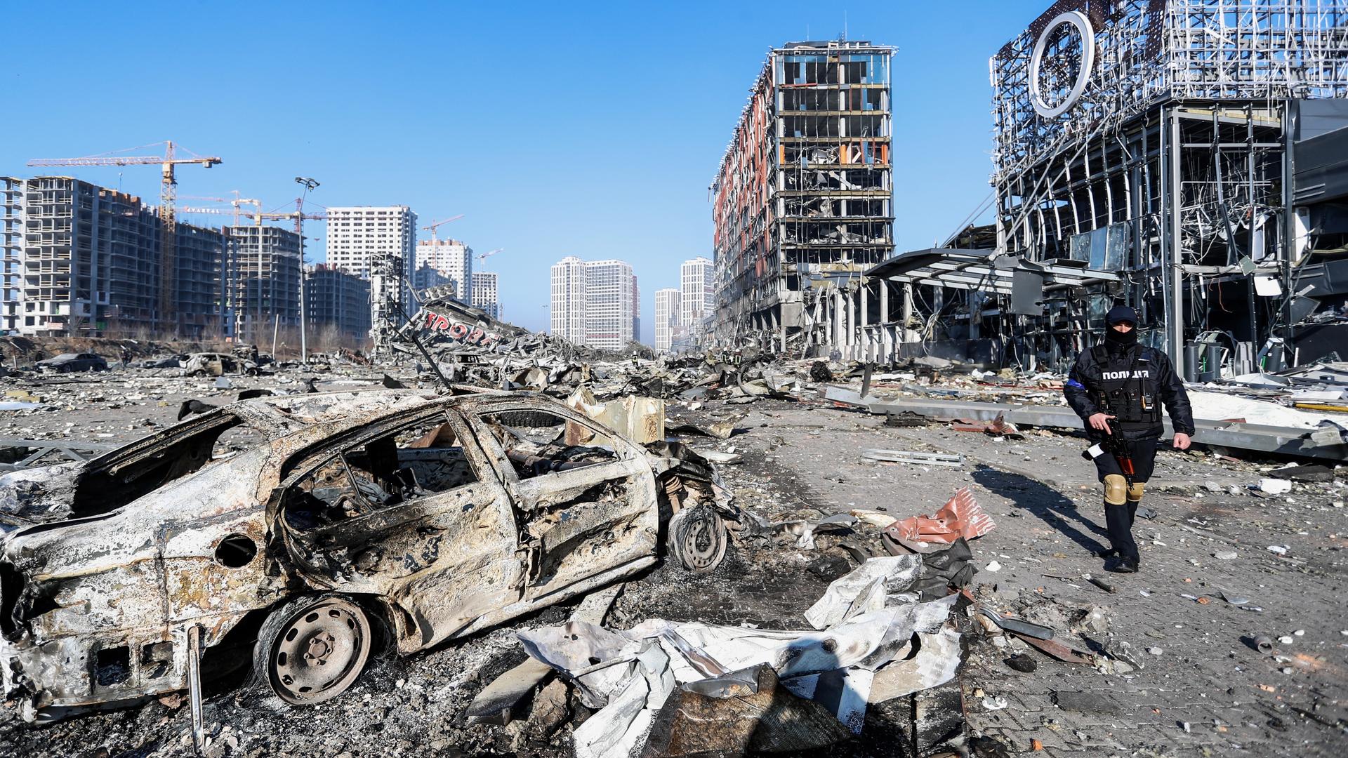 Die ukrainische Stadt Kiew nach einem russischen Luftschlag. Die Straßenflucht ist völlig zerstört, im Vordergrund ein ausgebranntes Auto. Die ukrainische Stadt Kiew nach einem russischen Luftschlag. Die Straßenflucht ist völlig zerstört, im Vordergrund ein ausgebranntes Auto.