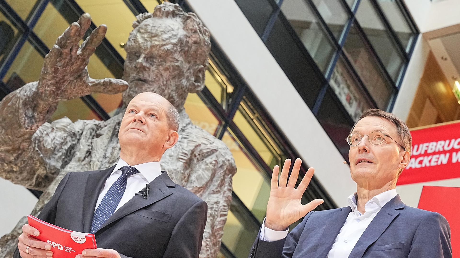 Die SPD-Politiker Olaf Scholz und Karl Lauterbach bei der Präsentation der sozialdemokratischen Ministerposten vor einer Statue von Willy Brandt. Die SPD-Politiker Olaf Scholz und Karl Lauterbach bei der Präsentation der sozialdemokratischen Ministerposten vor einer Statue von Willy Brandt.