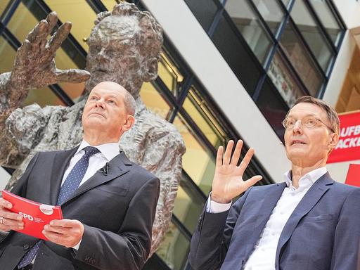 Die SPD-Politiker Olaf Scholz und Karl Lauterbach bei der Präsentation der sozialdemokratischen Ministerposten vor einer Statue von Willy Brandt. 