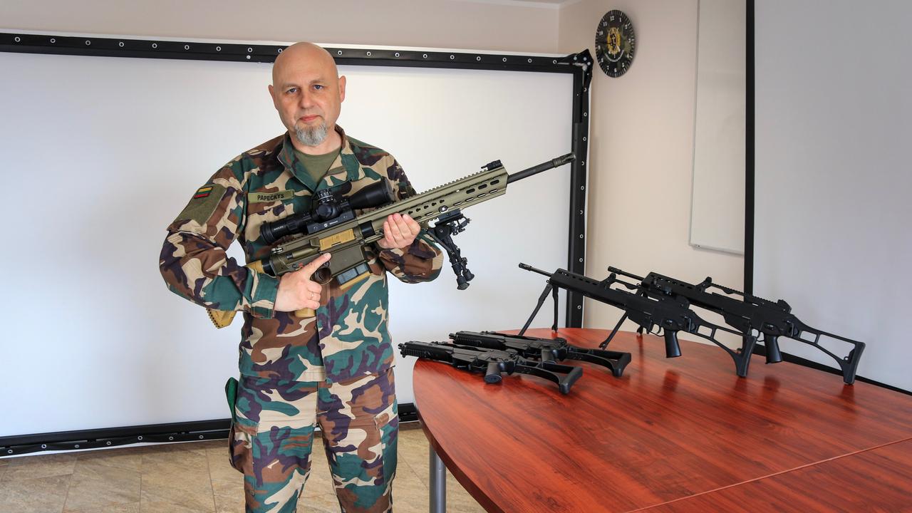 Mann in Tarnanzug hält ein Gewehr in der Hand Mann in Tarnanzug hält ein Gewehr in der Hand