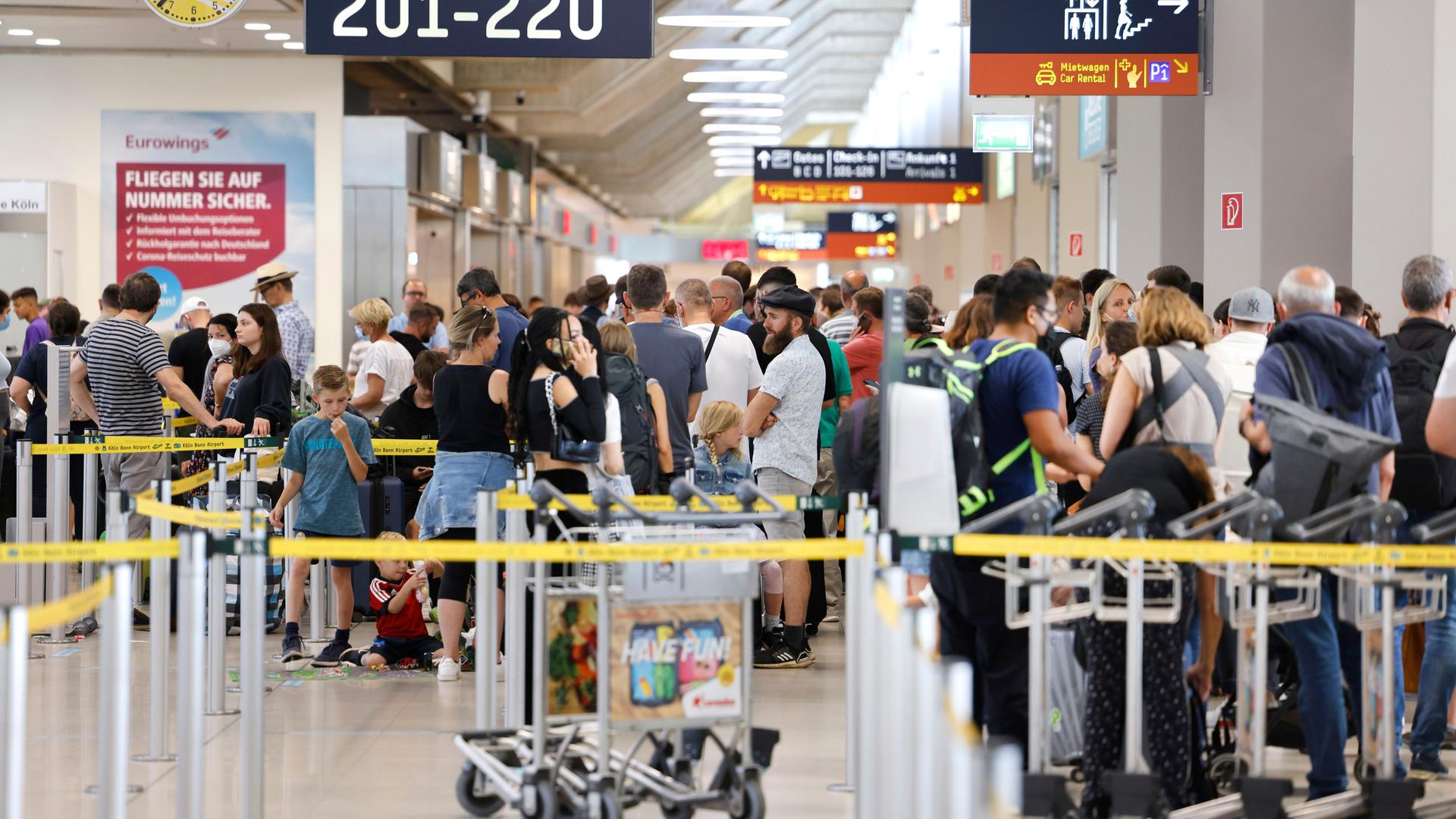 Menschen stehen in einer langen Schlange an. Sie warten auf die Sicherheits-Kontrolle am Flughafen Köln/Bonn. Menschen stehen in einer langen Schlange an. Sie warten auf die Sicherheits-Kontrolle am Flughafen Köln/Bonn.
