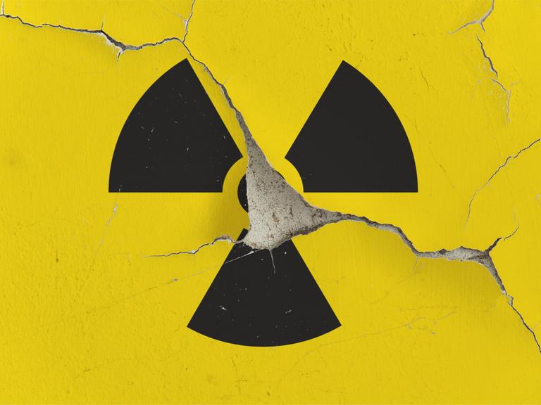 Auf einer Gebäudewand mit aufgeplatzter Fassade ist das Symbol für Radioaktivität zu sehen. 