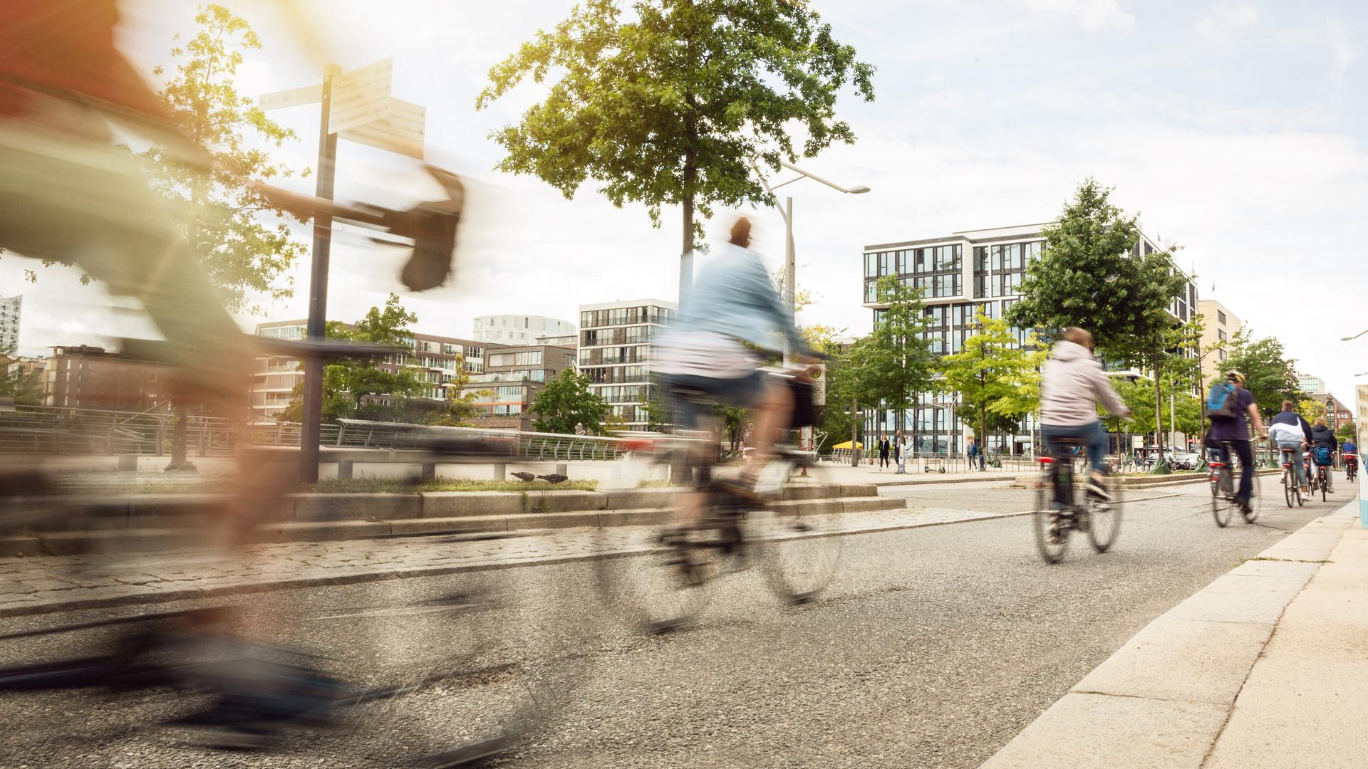 Straßenszene in einer Stadt mit auf einem breiten Fahrradweg fahrenden Fahrradfahrern.