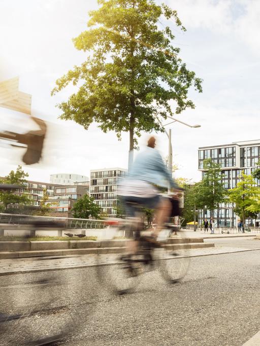 Straßenszene in einer Stadt mit auf einem breiten Fahrradweg fahrenden Fahrradfahrern.