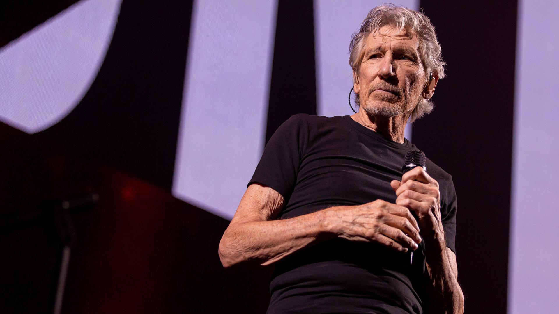 Roger Waters steht auf einer Bühne.