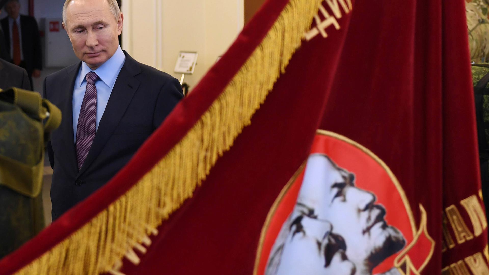 Der russische Präsident Wladimir Putin schaut auf ein Banner aus der Zeit der Sowjetunion, auf der Lenin und Stalin zu sehen sind. Der russische Präsident Wladimir Putin schaut auf ein Banner aus der Zeit der Sowjetunion, auf der Lenin und Stalin zu sehen sind.