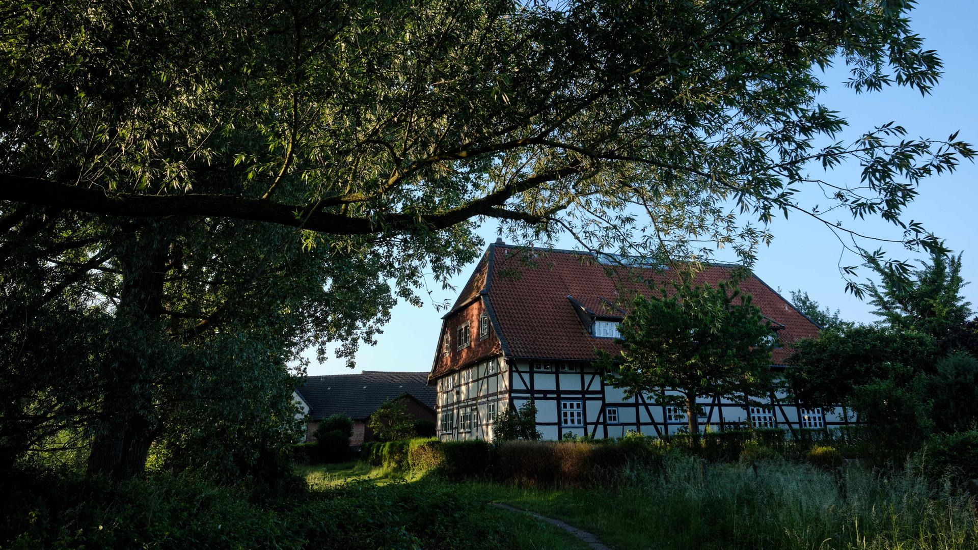 Ein Fachwerkhaus an einem Deich in der nördlichen Okeraue im Ortsteil Watenbüttel wird von der Sonne beschienen.