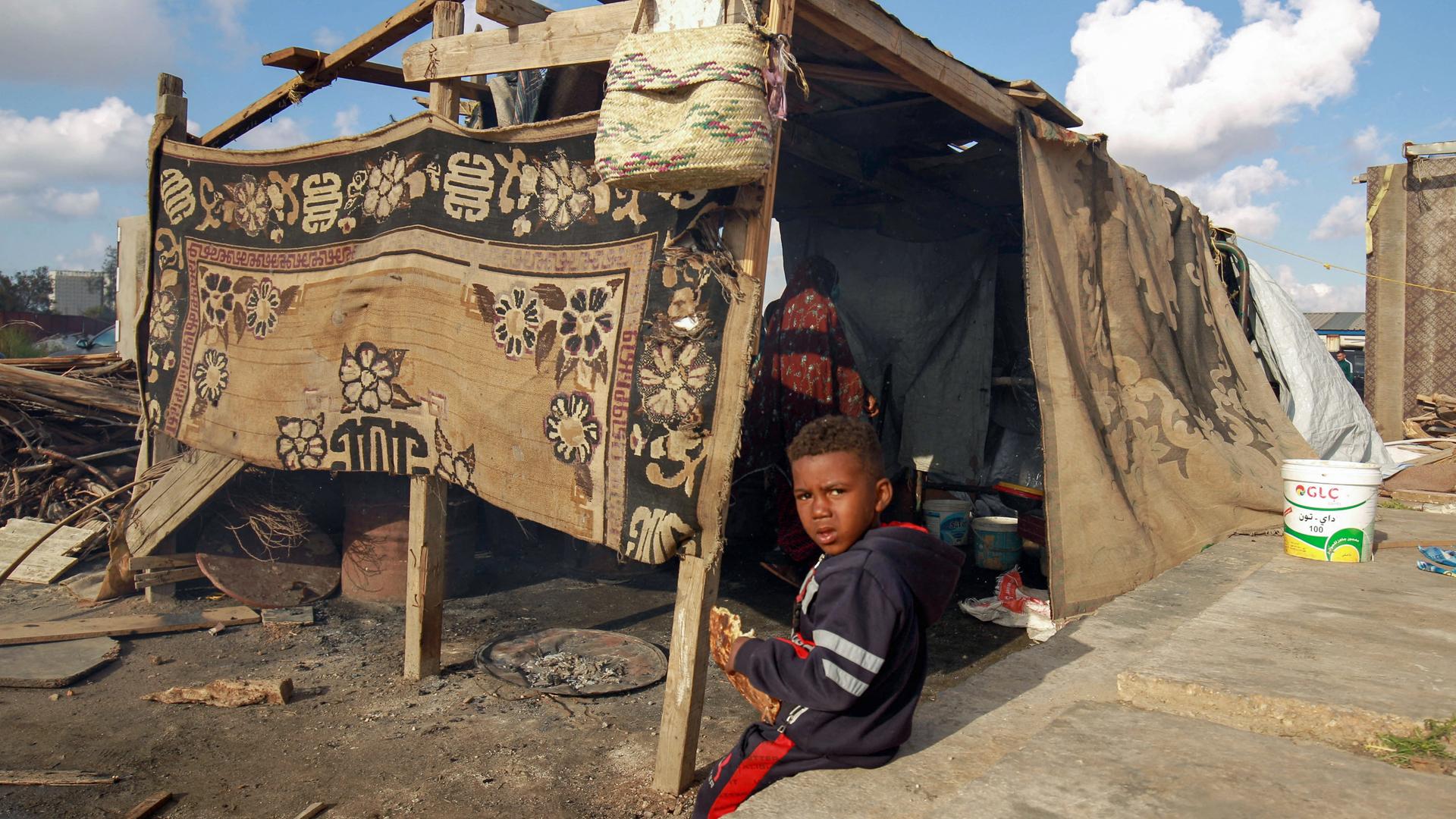 Ein kleiner Junge sitzt auf dem Boden eines mit Teppichen notdürftig verhangenen Zeltes in einem Lager in Benghazi in Libyen. Ein kleiner Junge sitzt auf dem Boden eines mit Teppichen notdürftig verhangenen Zeltes in einem Lager in Benghazi in Libyen.