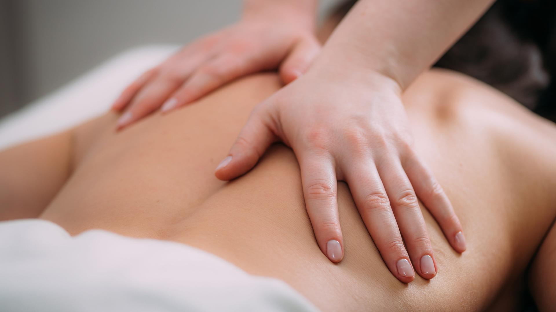 Eine Person auf einer Liege bekommt eine Rückenmassage Eine Person auf einer Liege bekommt eine Rückenmassage