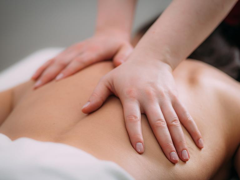 Eine Person auf einer Liege bekommt eine Rückenmassage