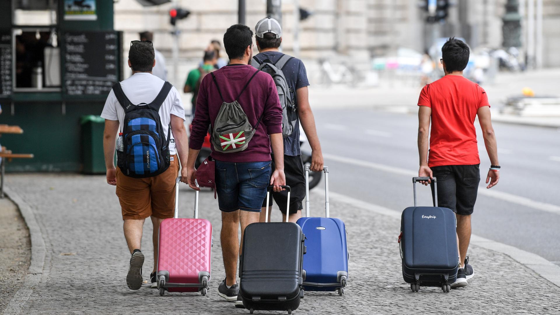 Touristen gehen mit Rollkoffern einen Gehweg in Berlin-Mitte entlang.