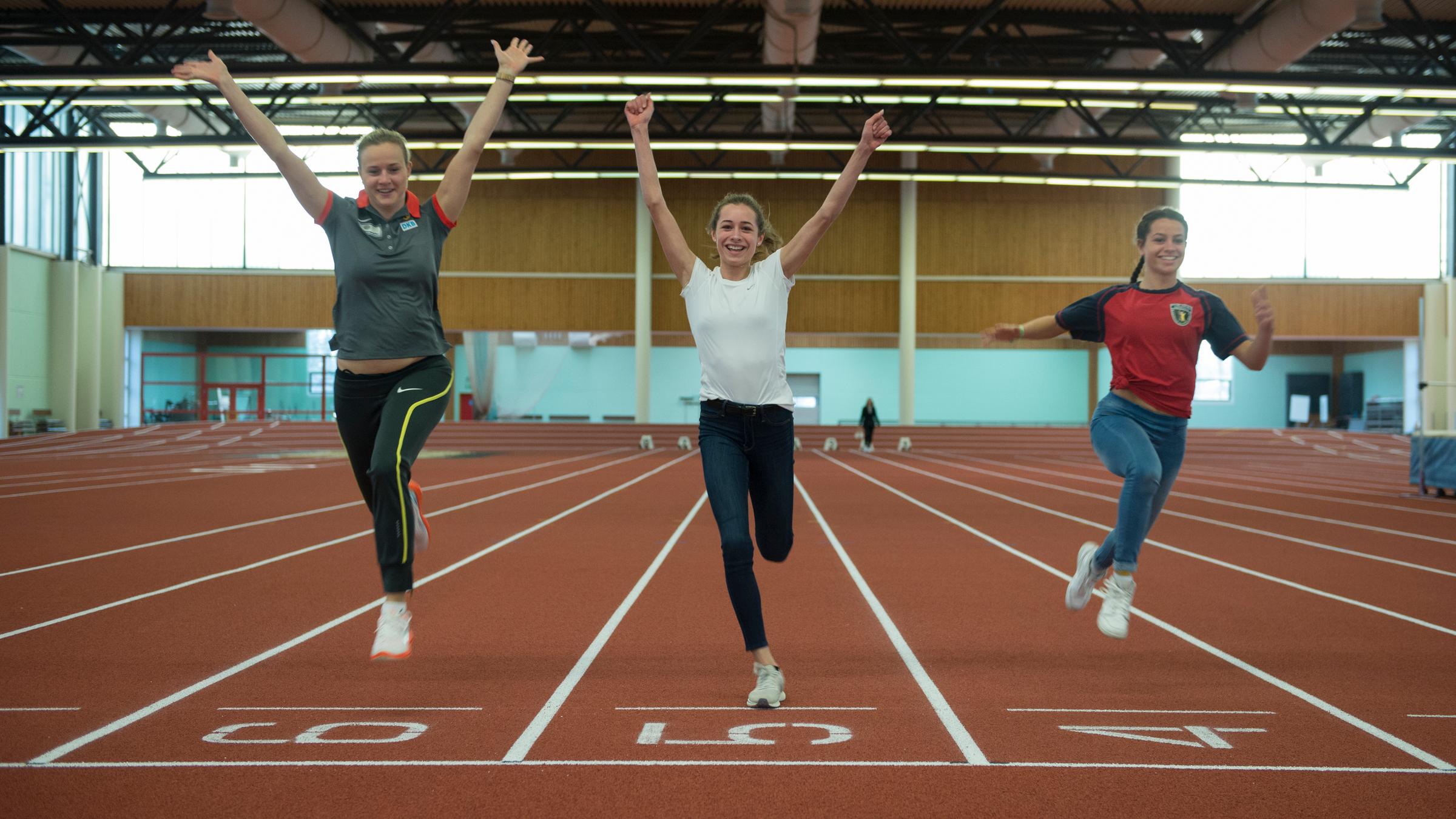 Schülerinnen der Berliner Poelchau-Schule im Olympiapark laufen mit Weitspringerin Melanie Bauschke durchs Ziel.