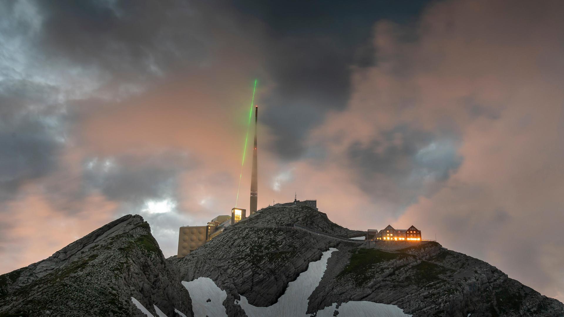 Ein grüner Laser strahlt von der Bergspitze des Säntis in den Himmel. Ein grüner Laser strahlt von der Bergspitze des Säntis in den Himmel.