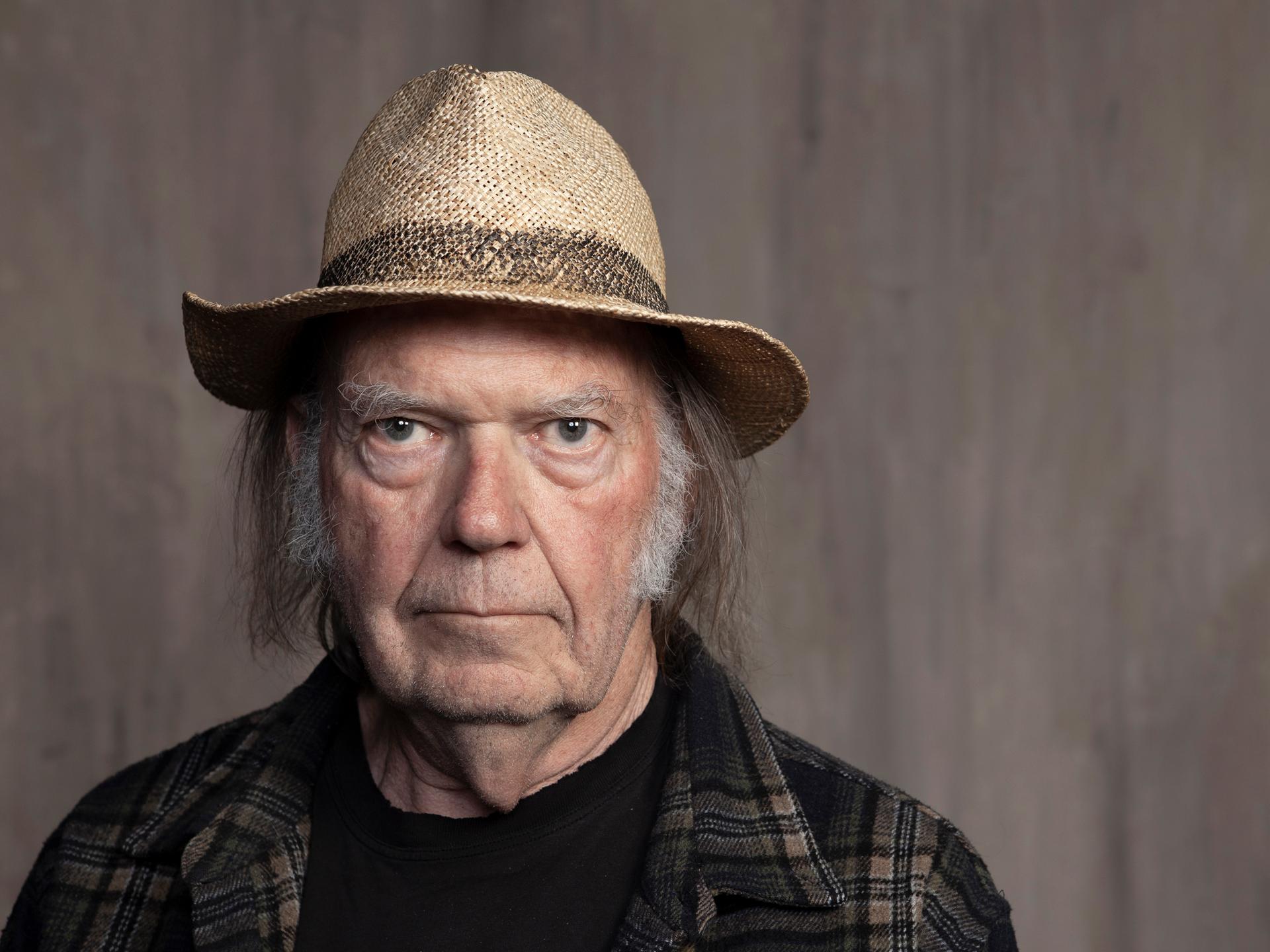 Neil Young posiert mit Hut und Flannellhemd.
