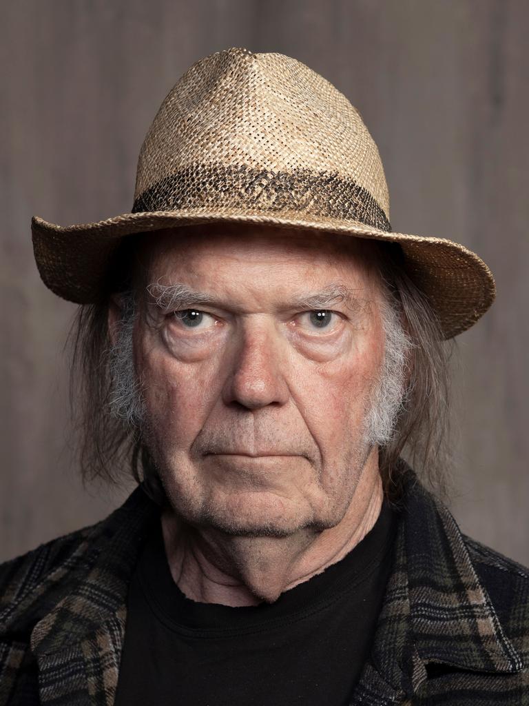 Neil Young posiert mit Hut und Flannellhemd.