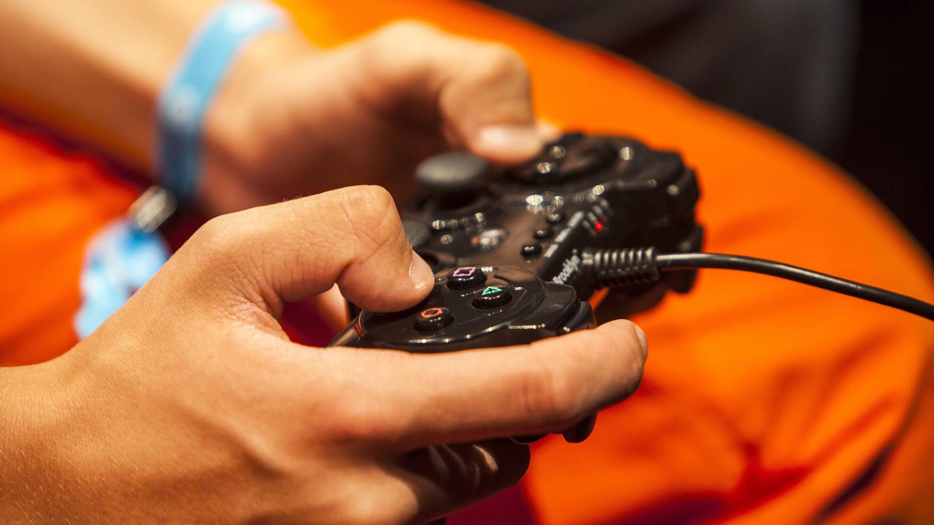 Symbolbild für die Gefahren für Jugendliche bei der unbeaufsichtigten Internetnutzung: Ein Heranwachsender hat den Controller eines Videospiels in der Hand. 