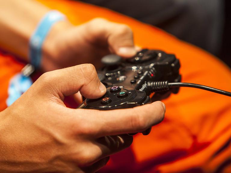 Symbolbild für die Gefahren für Jugendliche bei der unbeaufsichtigten Internetnutzung: Ein Heranwachsender hat den Controller eines Videospiels in der Hand. 