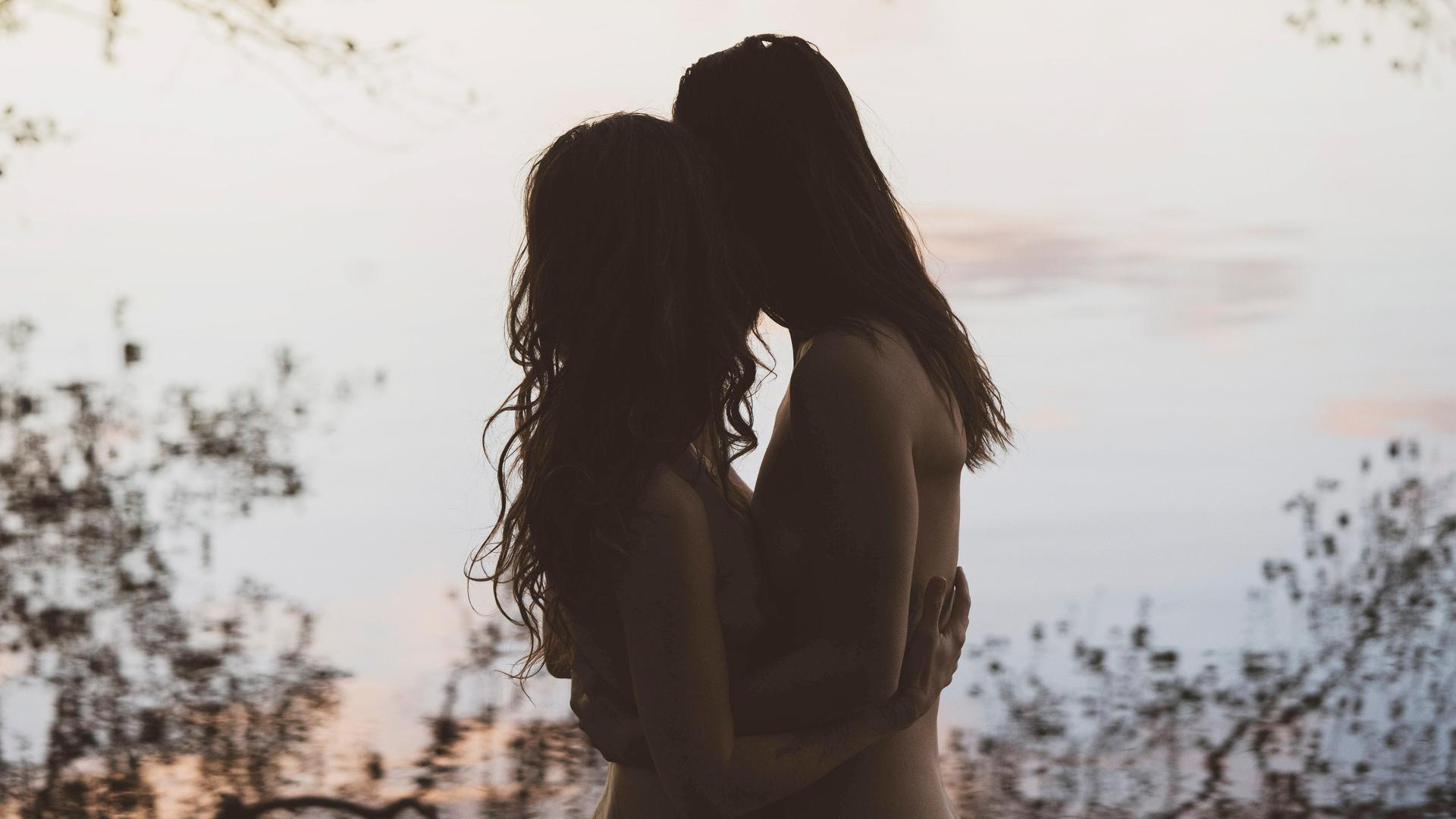 Die Silhouette eines Frauenpaares die sich umarmen, in romantischer Lichtstimmung vor einem See in Brandenburg. Die Silhouette eines Frauenpaares die sich umarmen, in romantischer Lichtstimmung vor einem See in Brandenburg.