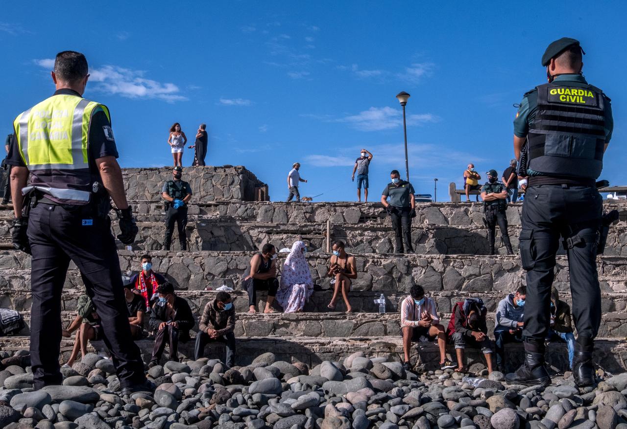 Zwei Sicherheitskräfte beobachten Migranten, die gerade mit einem Boot an der Küste von Gran Canaria gestrandet sind. Zwei Sicherheitskräfte beobachten Migranten, die gerade mit einem Boot an der Küste von Gran Canaria gestrandet sind.