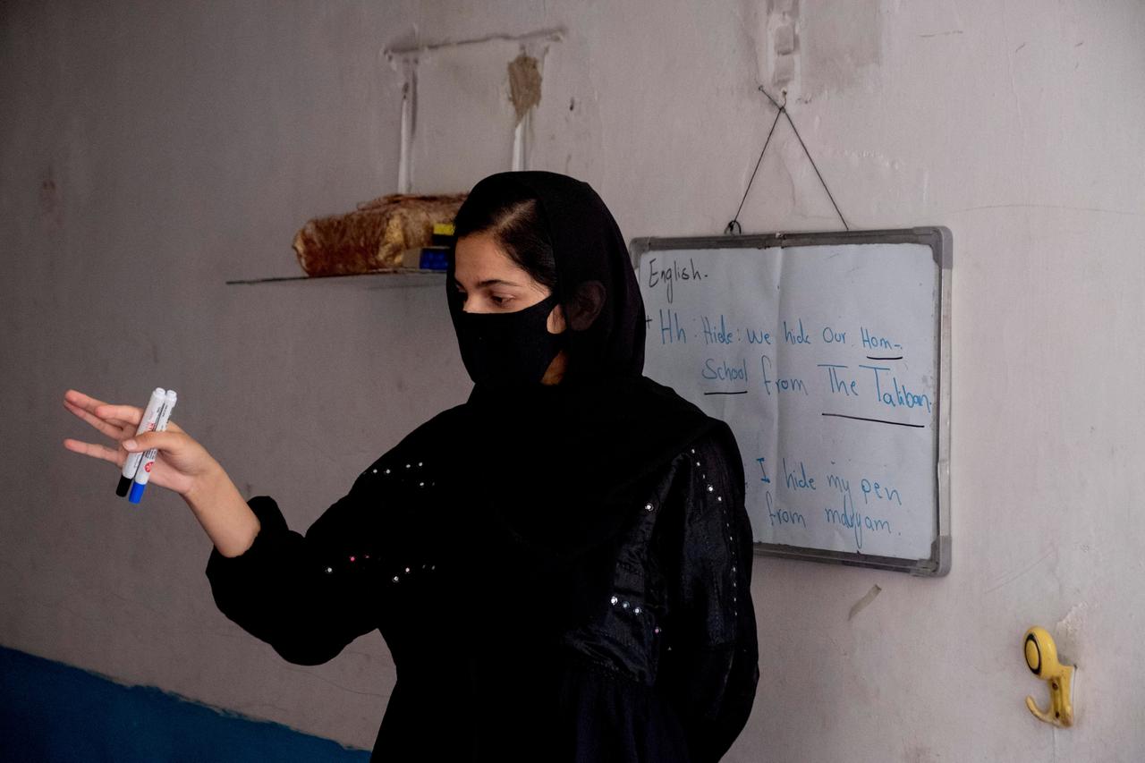 Eine verhüllte Lehrerin, auf einer Tafel stehen englische Sätze, u.a.: "Wir verstecken unseren Privatunterricht vor den Taliban" Eine verhüllte Lehrerin, auf einer Tafel stehen englische Sätze, u.a.: "Wir verstecken unseren Privatunterricht vor den Taliban"