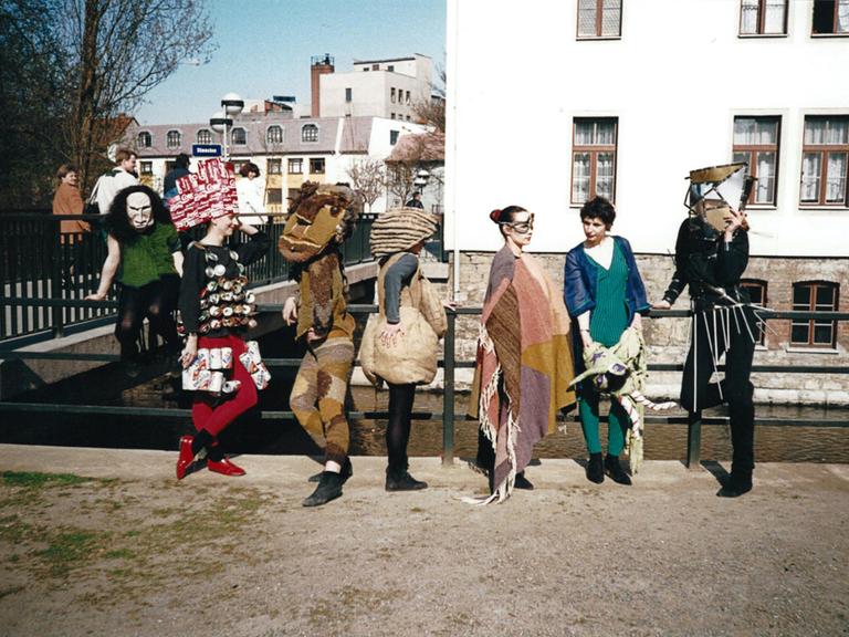 Sieben Frauen in bunten Kostümen lehnen sich an ein Geländer.