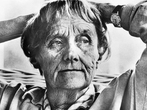 Das Schwarz-Weiß-Foto zeigt eine rund 80 Jahre alte Frau, die sich zurücklehnt und die Hände hinter dem Kopf verschränkt. 