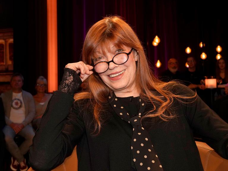 Die Sängerin und Schauspielerin Katja Ebstein schaut über den Rand ihrer Brille und lächelt in die Kamera.