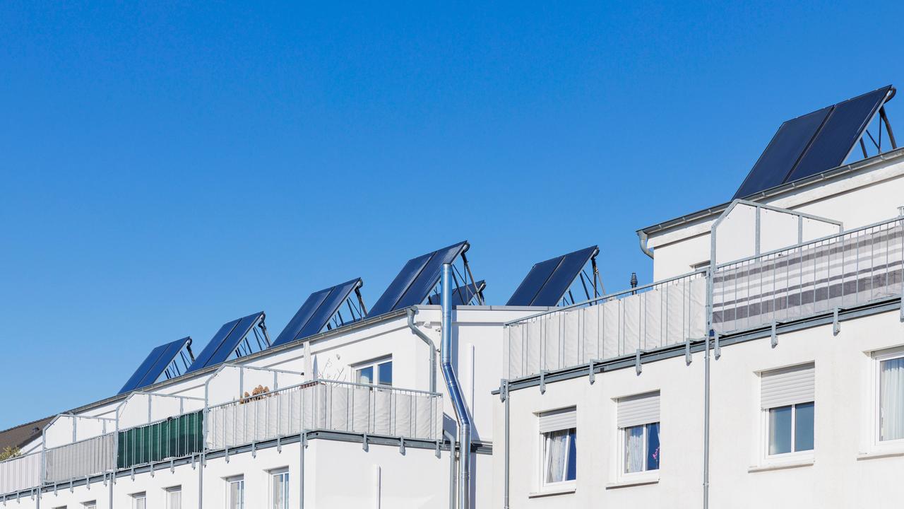 Blick auf ein Mehrfamilienhaus mit mehreren Solarflächen auf dem Dach.