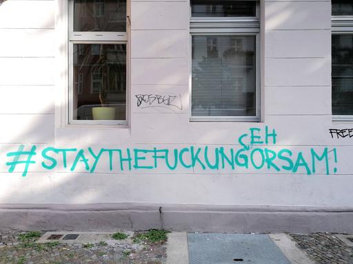 "Stay the fuck ungehorsam steht an einer Hauswand in Berlin
