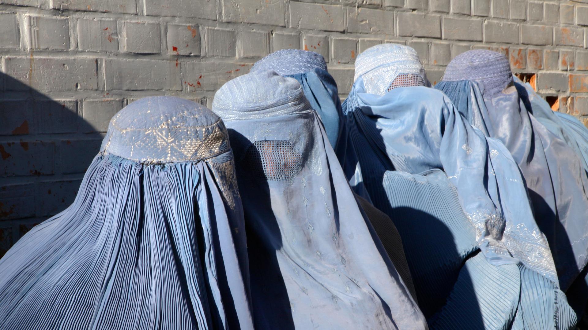 Mehrere Frauen in Afghanistan sind komplett mit blauen Gewändern verhüllt. Mehrere Frauen in Afghanistan sind komplett mit blauen Gewändern verhüllt.