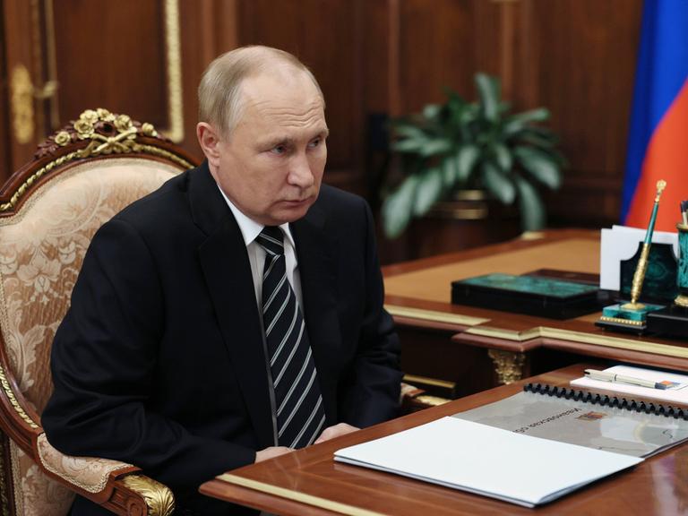 Wladimir Putin sitzt an einem Tisch.